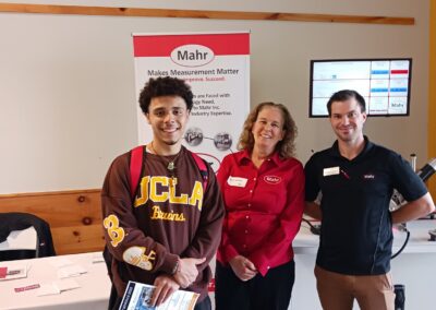 A student stands next to 2 representatives from Mahr