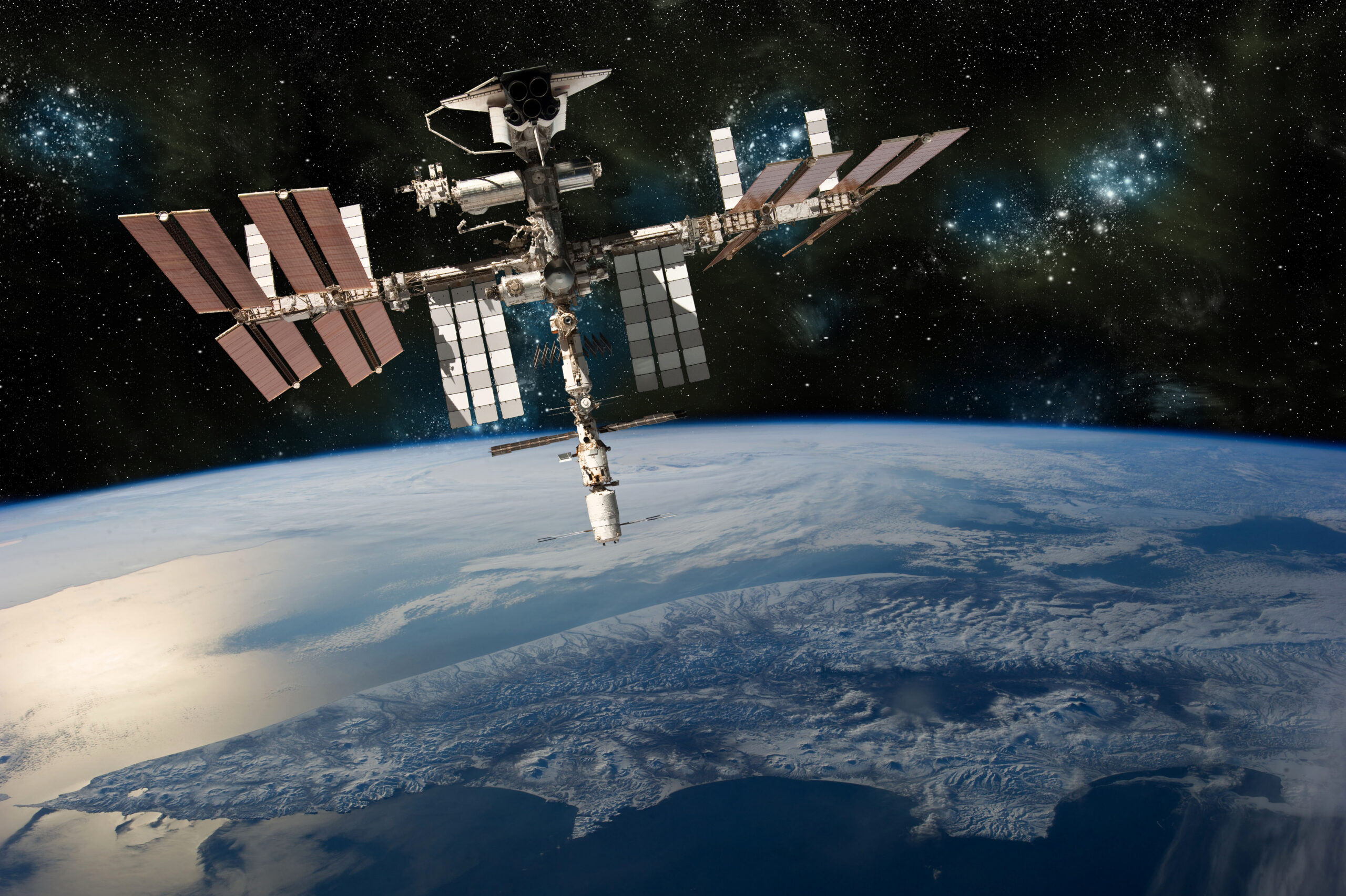 A depiction of the space shuttle docked at the international space station orbiting Earth. -  Elements of this image furnished by NASA
